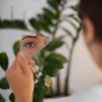 portrait young woman with low self esteem looking hand held mirror